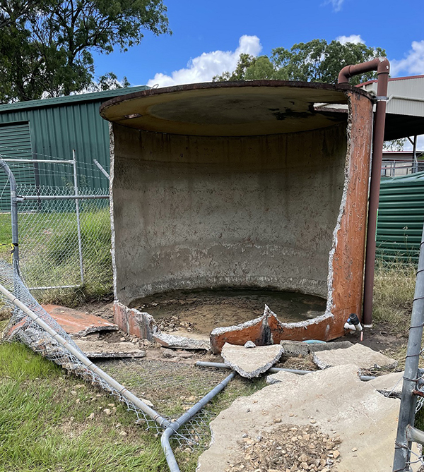 Failed tank showing concrete fragments and damaged fencing