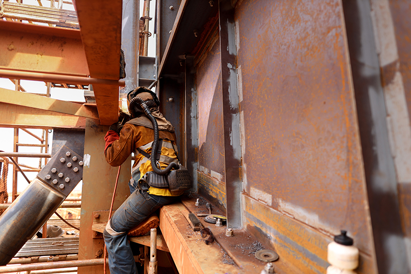 Worker welding wearing an air-fed welding helmet